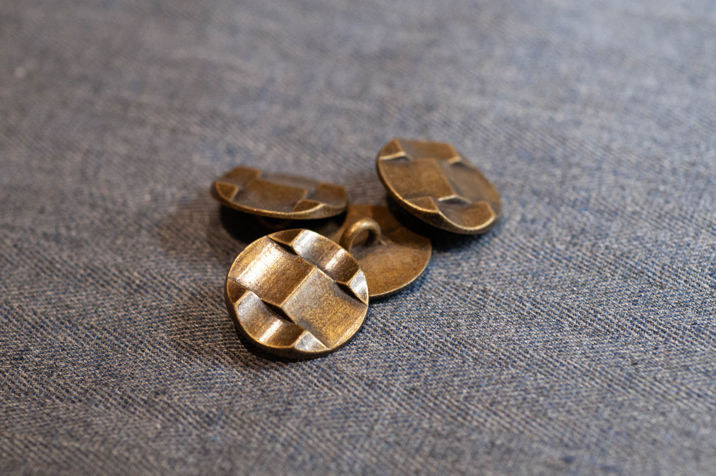 Three bronze buttons on a textured fabric background