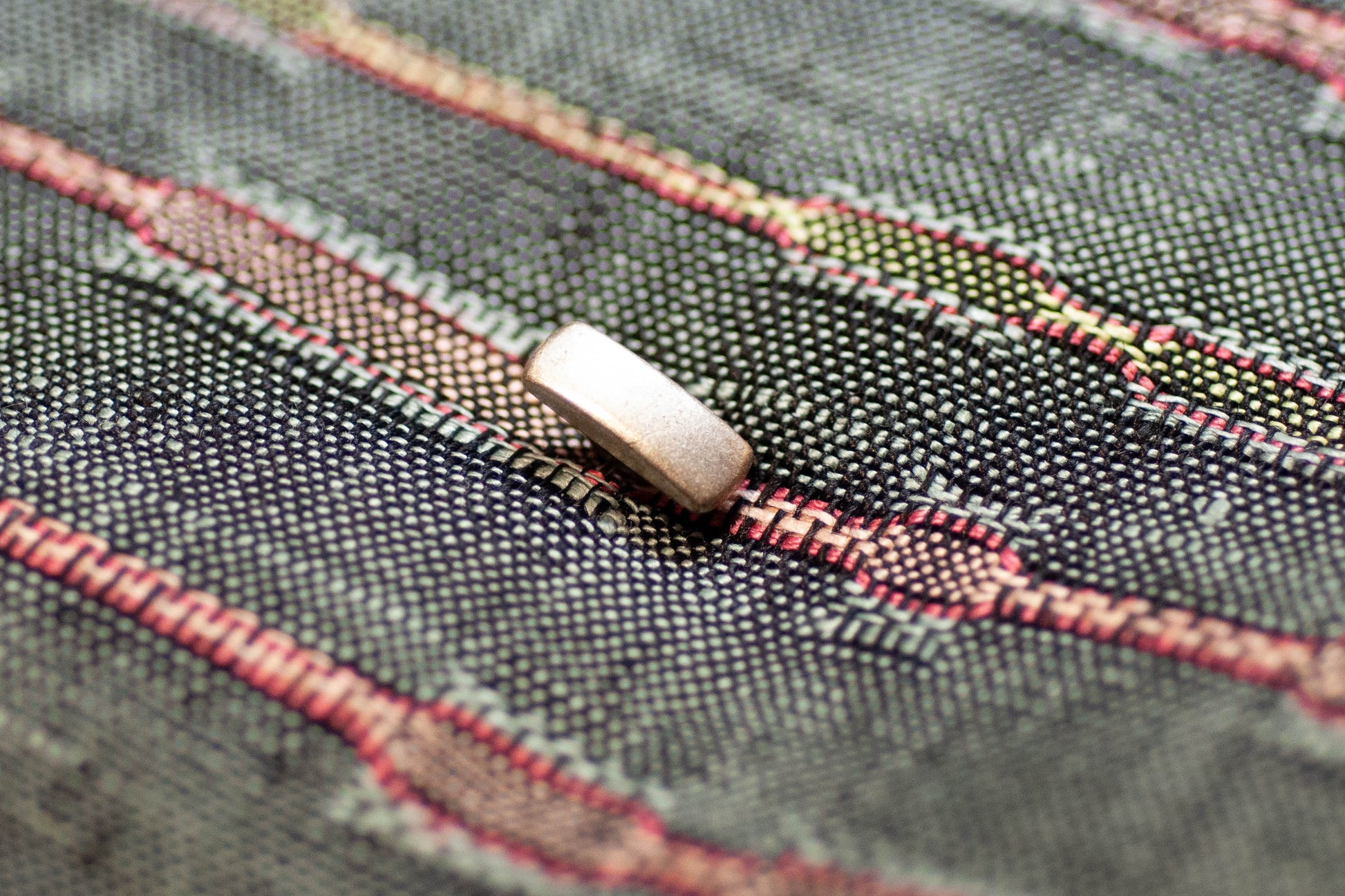 Close-up of a button on fabric with red and green thread